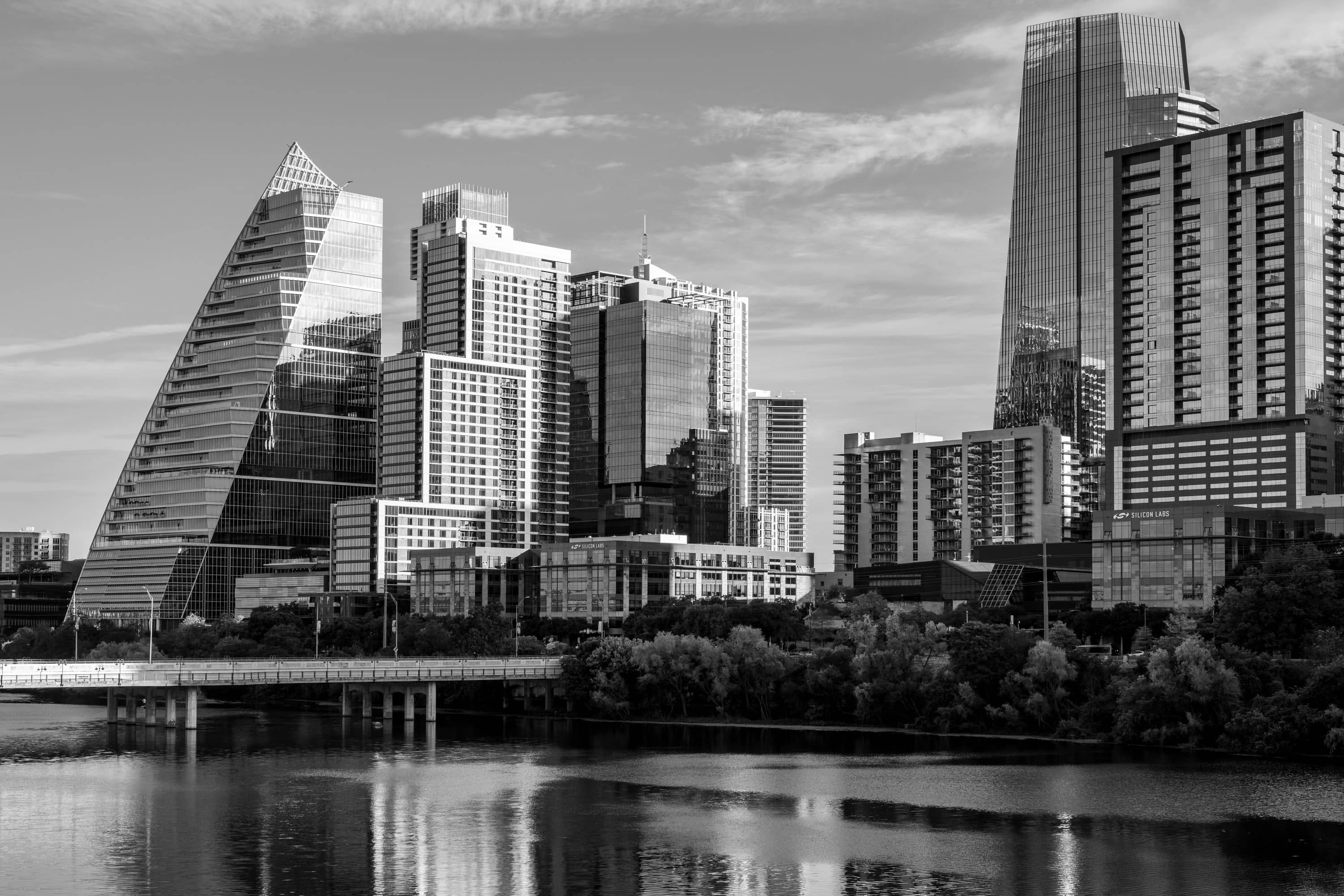 The downtown Austin skyline at dusk, towers lit against a darkening sky with the Capitol dome held clear between them.