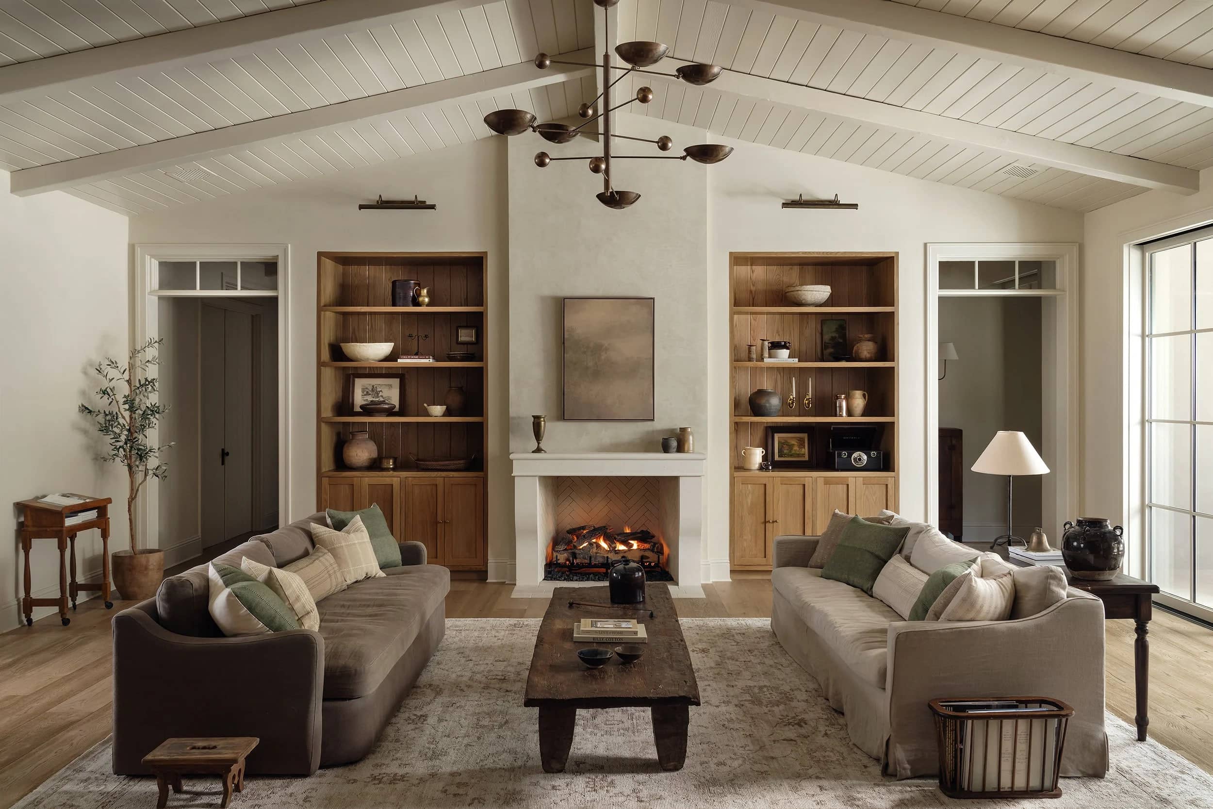 A living room with a limestone fireplace set between white oak built-ins.
